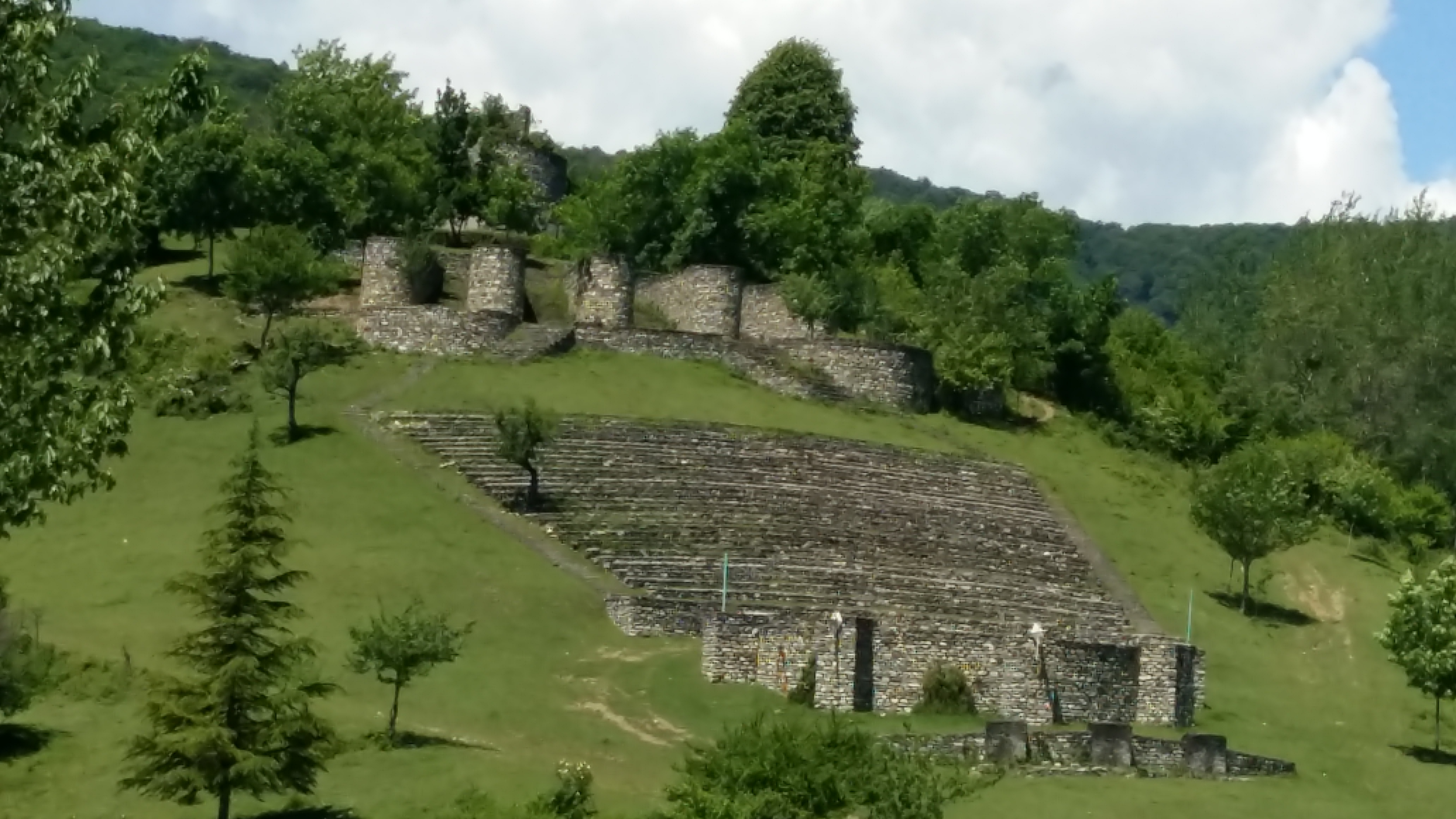Image of a stone amphitheatre with castle-like bastions on a hillside.