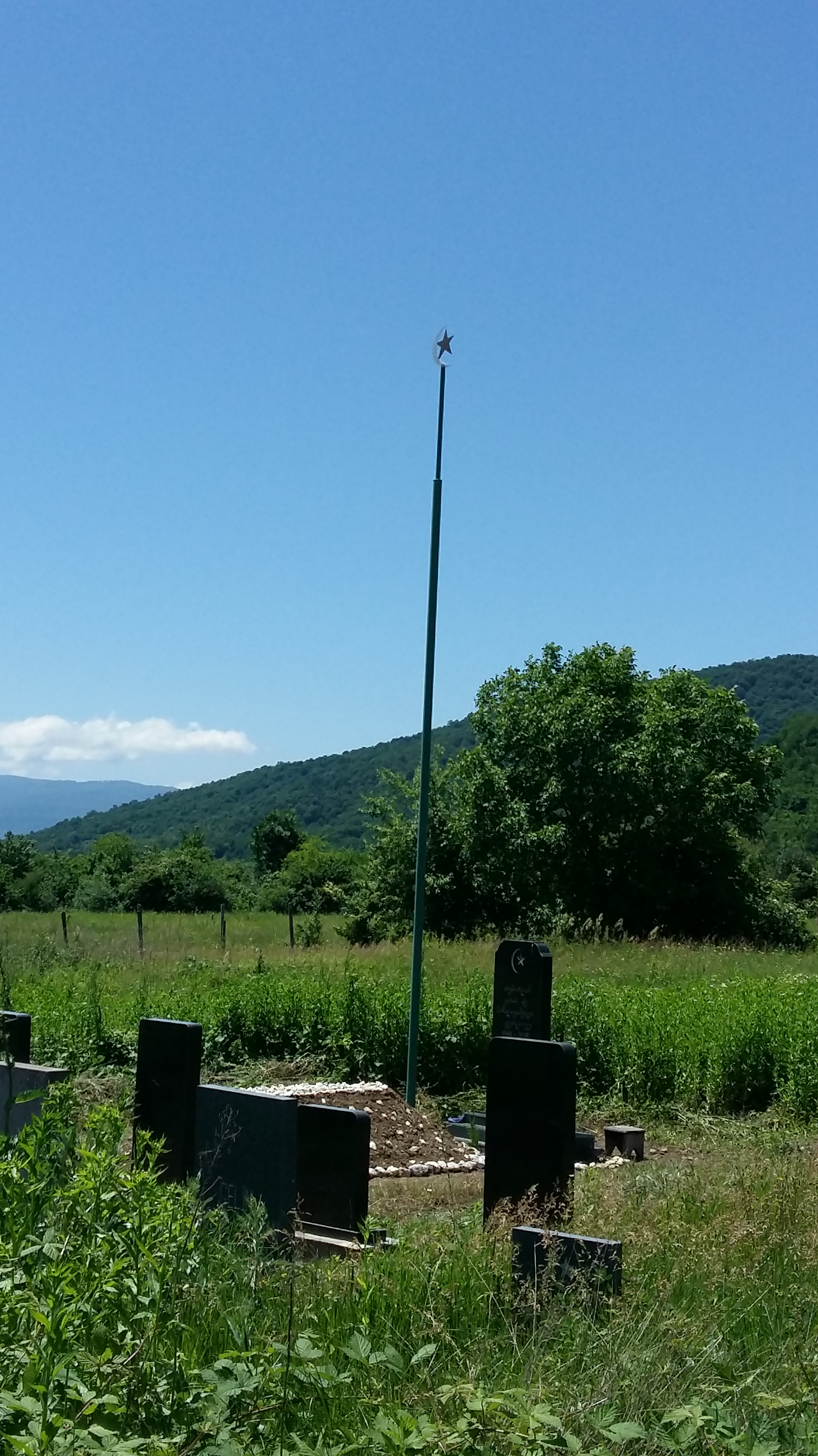 Image of a grave with a flagpole topped by a crescent moon and star.