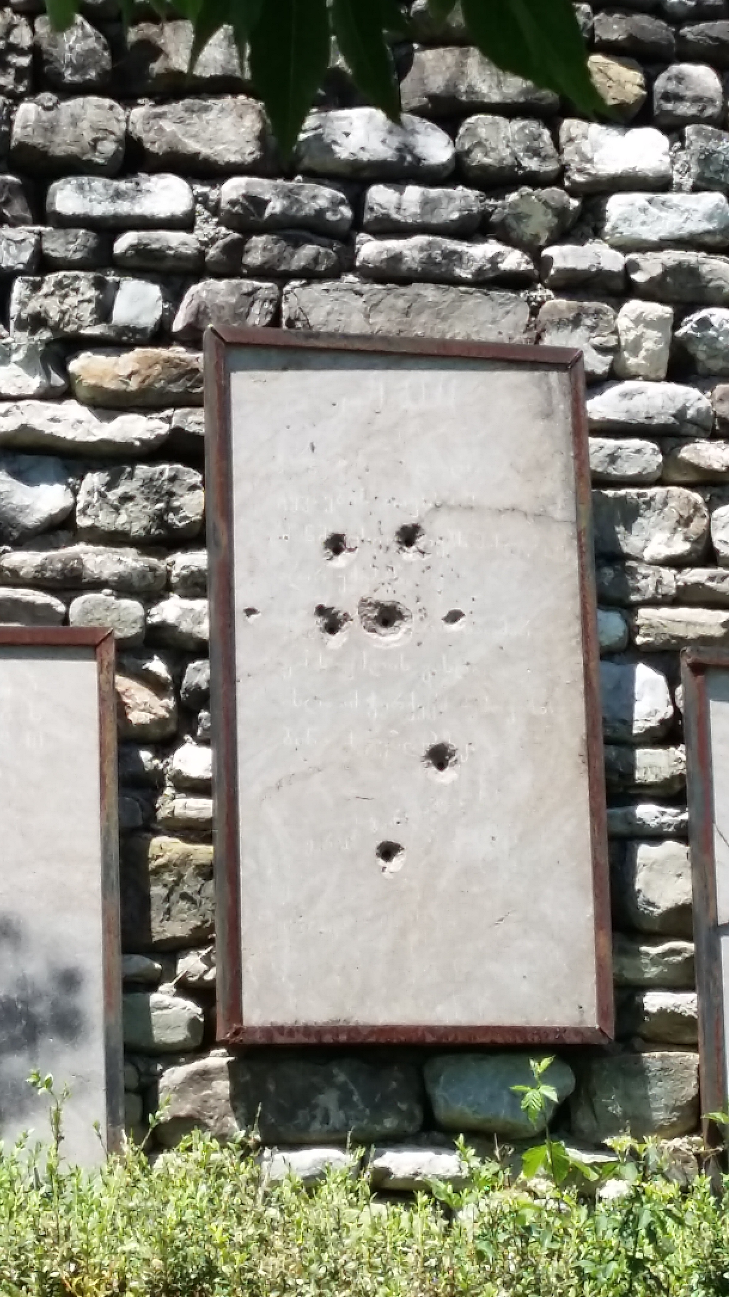 Concrete plaque with bullet holes in it.