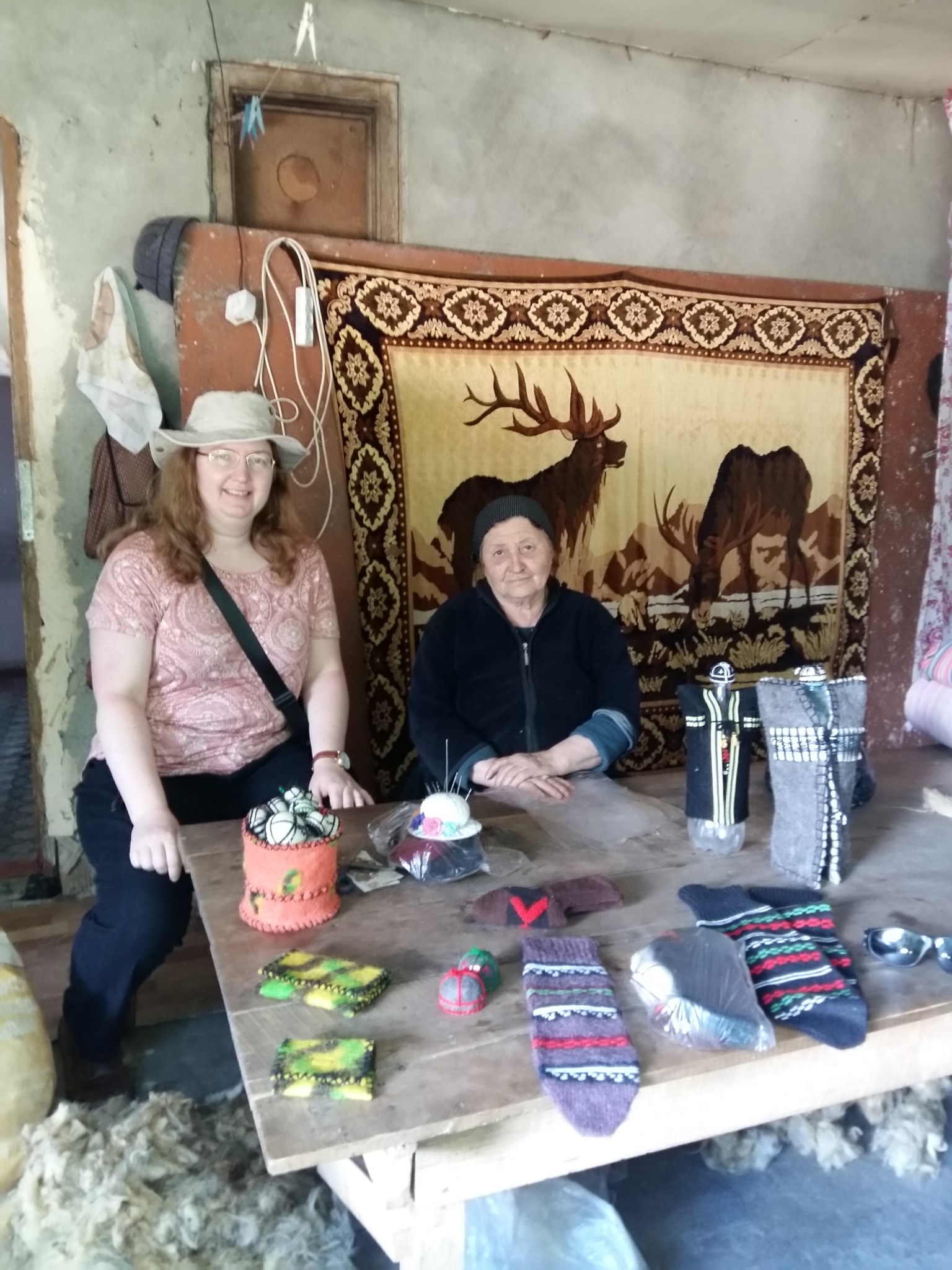 Two women behind a table with wool and felt souvenirs on it.