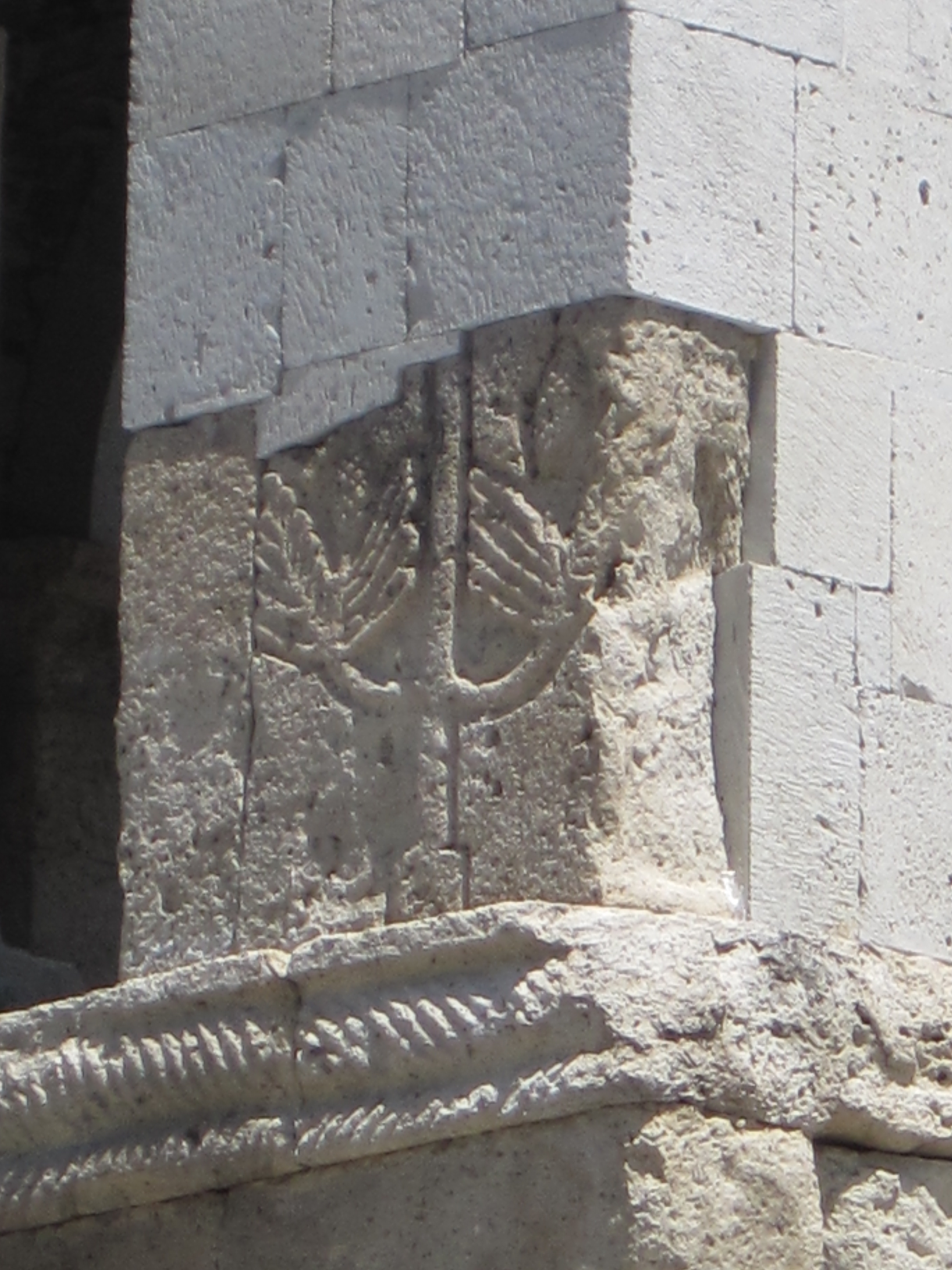 Wall made with concrete blocks on top of stone blocks with bas relief carving.