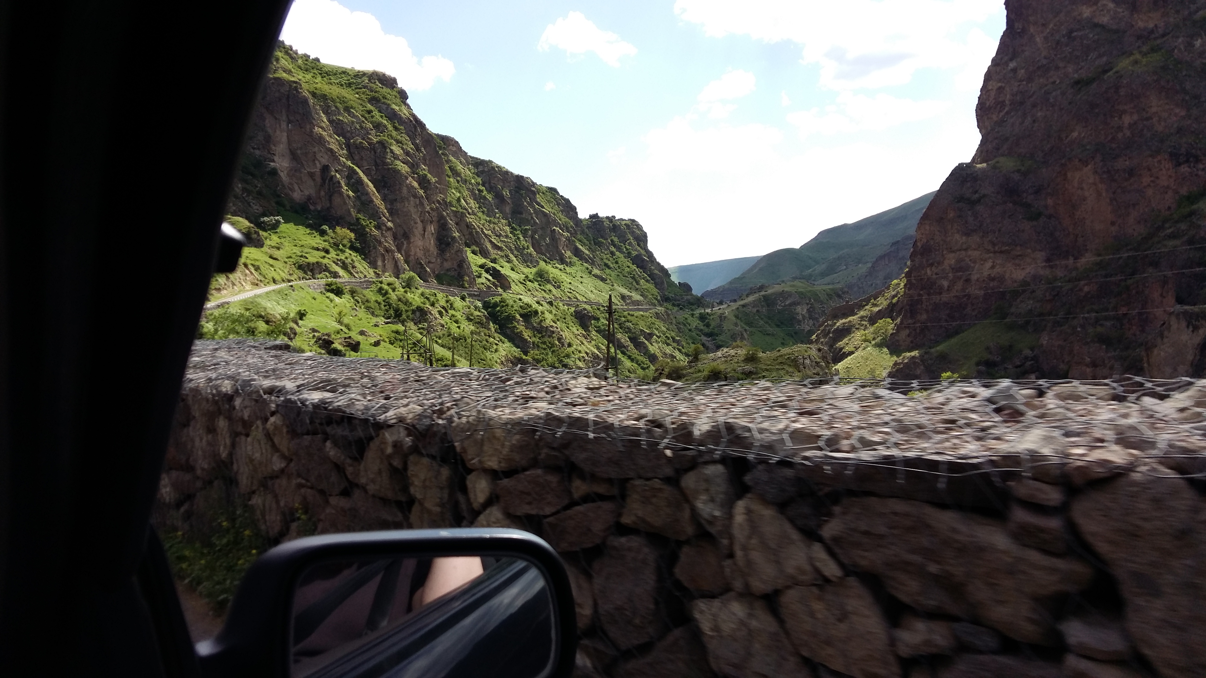 A stone wall and a mountain gorge seen through a car window.