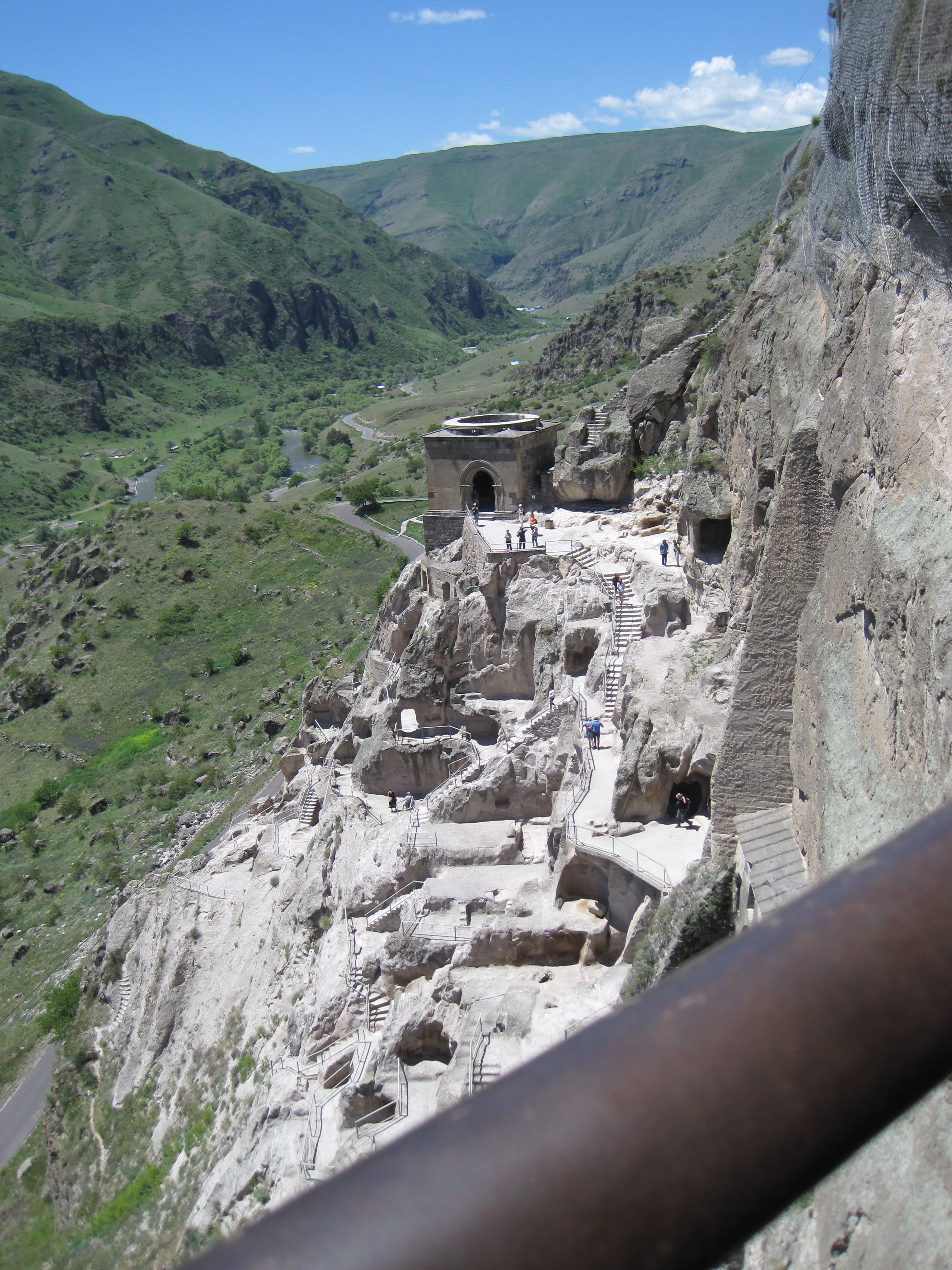 View upriver from Vardzia, with caves and a square bell tower below.