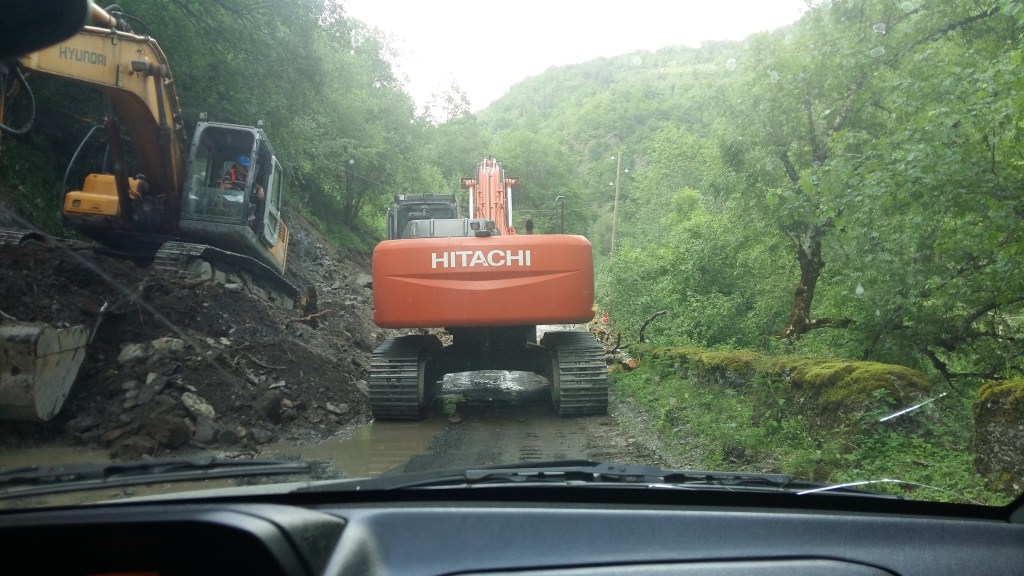 The backside of an excavator on a narrow mountain road.
