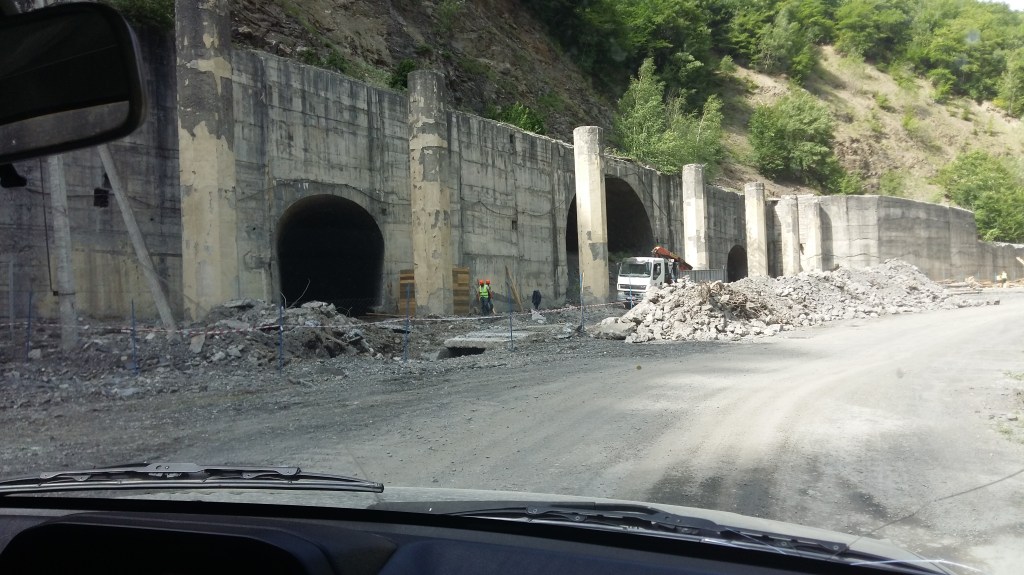 Entrances to tunnels in a mountainside at the side of the road.